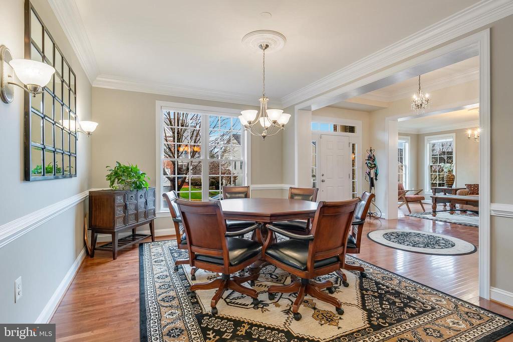 Dining room with a wooden table, upholstered chairs, chandelier, and ornate patterned rug.