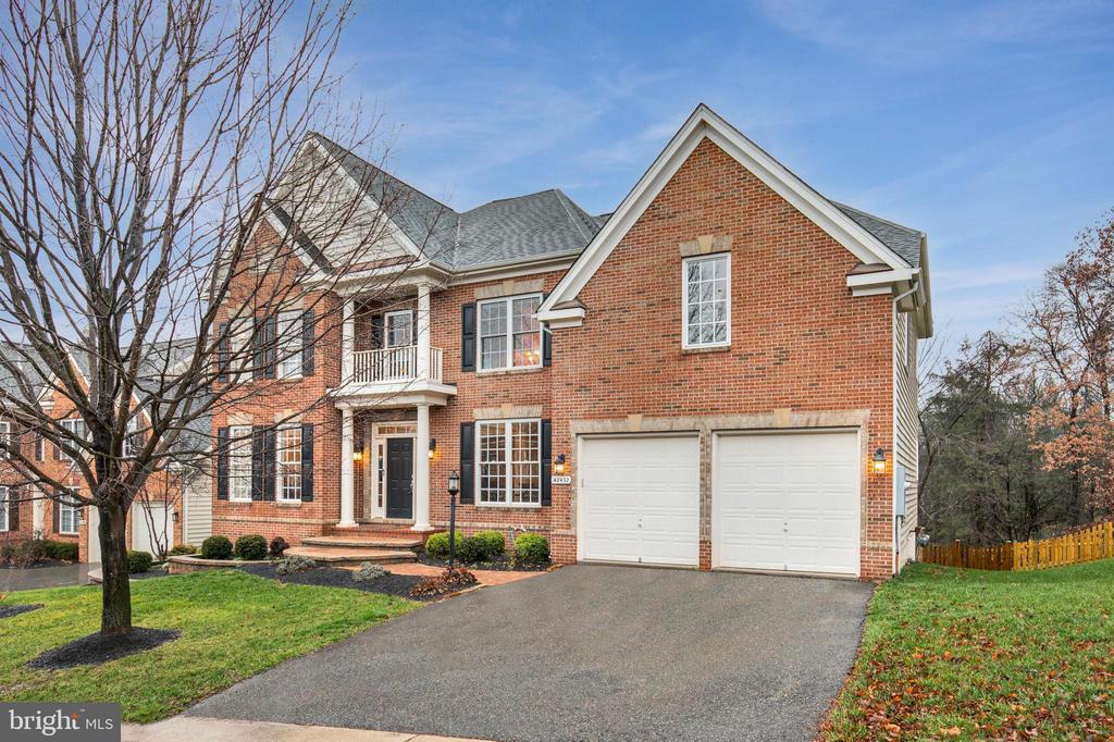 Brick two-story house with a double garage, front driveway, and small upper balcony.