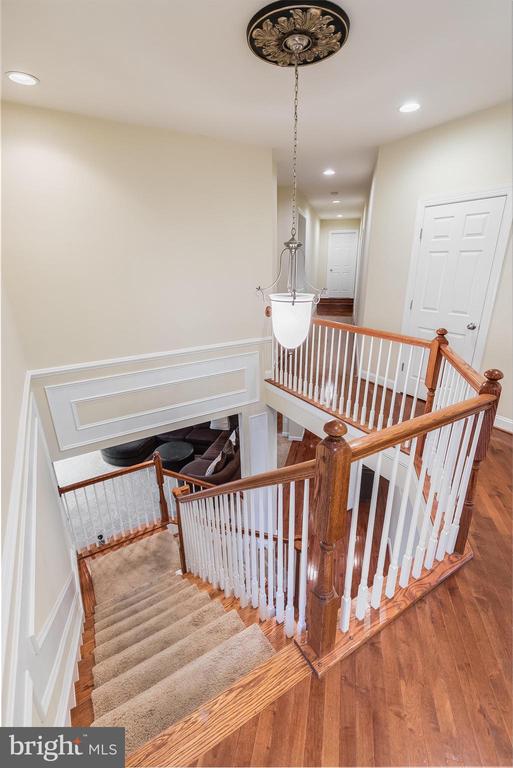 Two-story foyer with carpeted stairs, white balusters, wood railings and a hanging light.