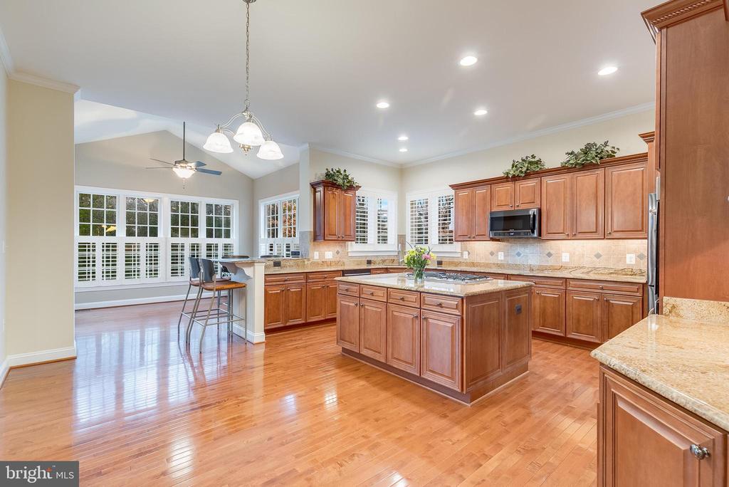 Kitchen with a wood-paneled island and granite counters, opening to a bright breakfast area with large windows.