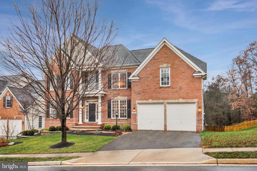 Two-story brick house with a covered entry, leafless front-yard tree, and two-car garage.