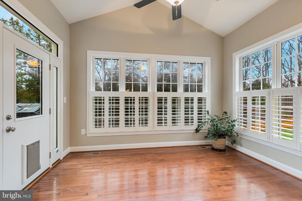 Bright room with hardwood floors, vaulted ceiling, and large shuttered windows.