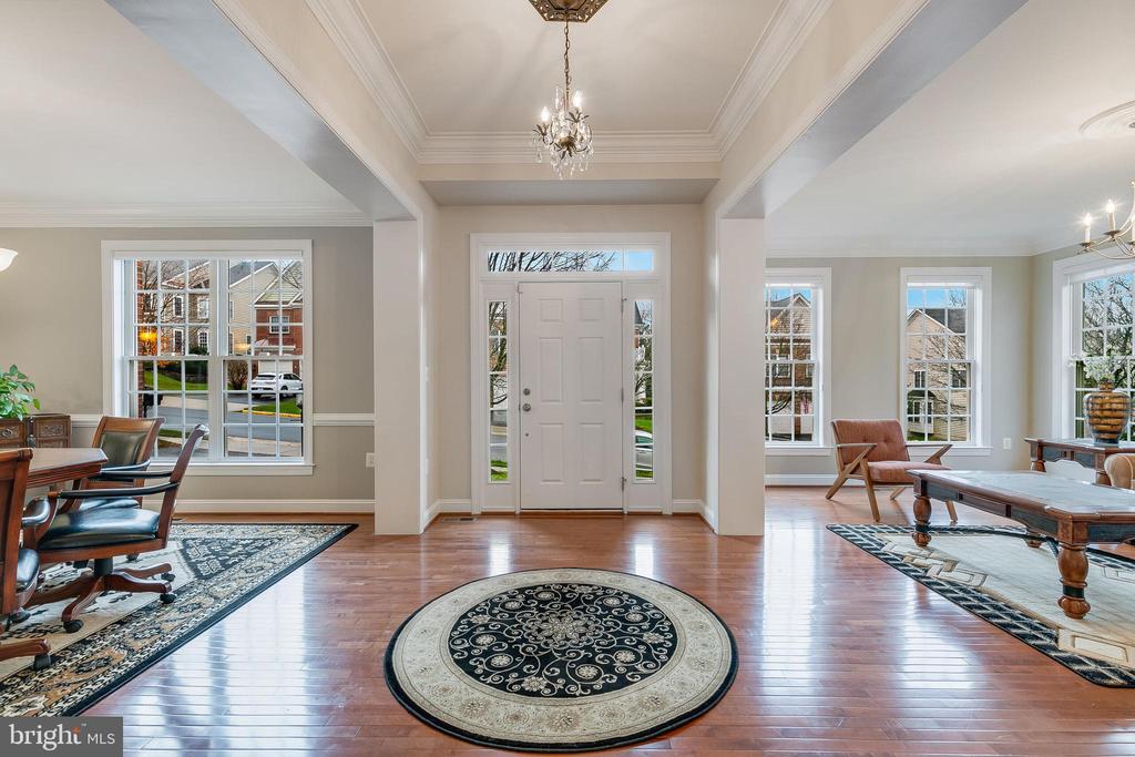 Entry foyer with hardwood floors, a round patterned rug, and a crystal chandelier.
