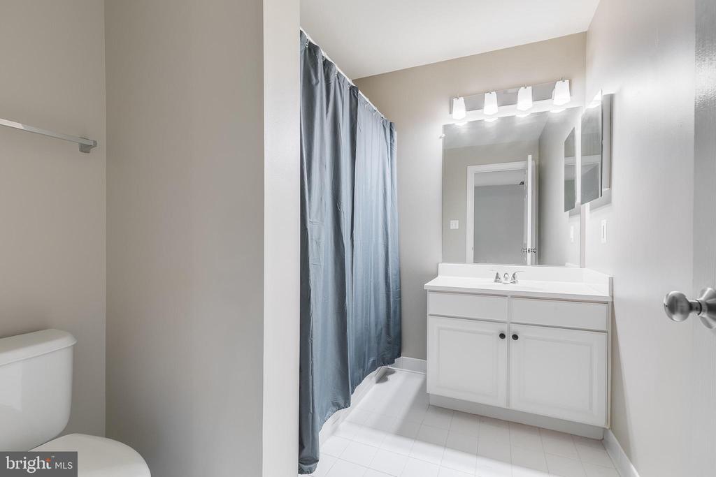 Bathroom with a white vanity, blue shower curtain, and partially visible toilet.