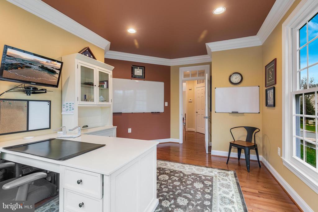 Home office with a white work island, wall-mounted whiteboards, and tall windows.
