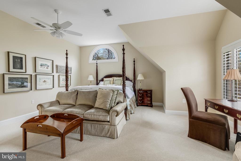 Bedroom with a four-poster bed, beige sofa, and arched window.