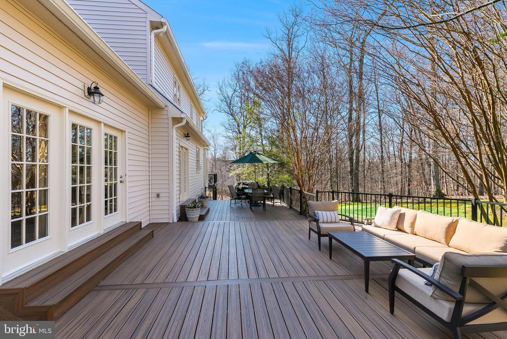 Furnished deck with patio seating, black railing, and a wooded view.