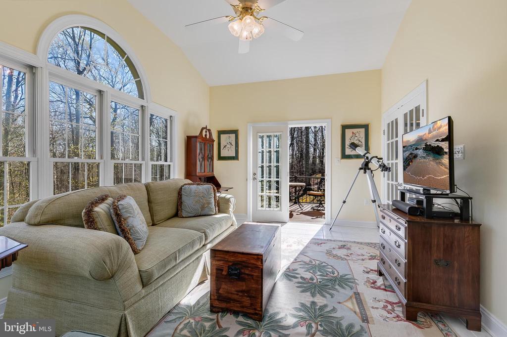 Living room with arched windows, a telescope, and a glass door opening onto a wooded deck.
