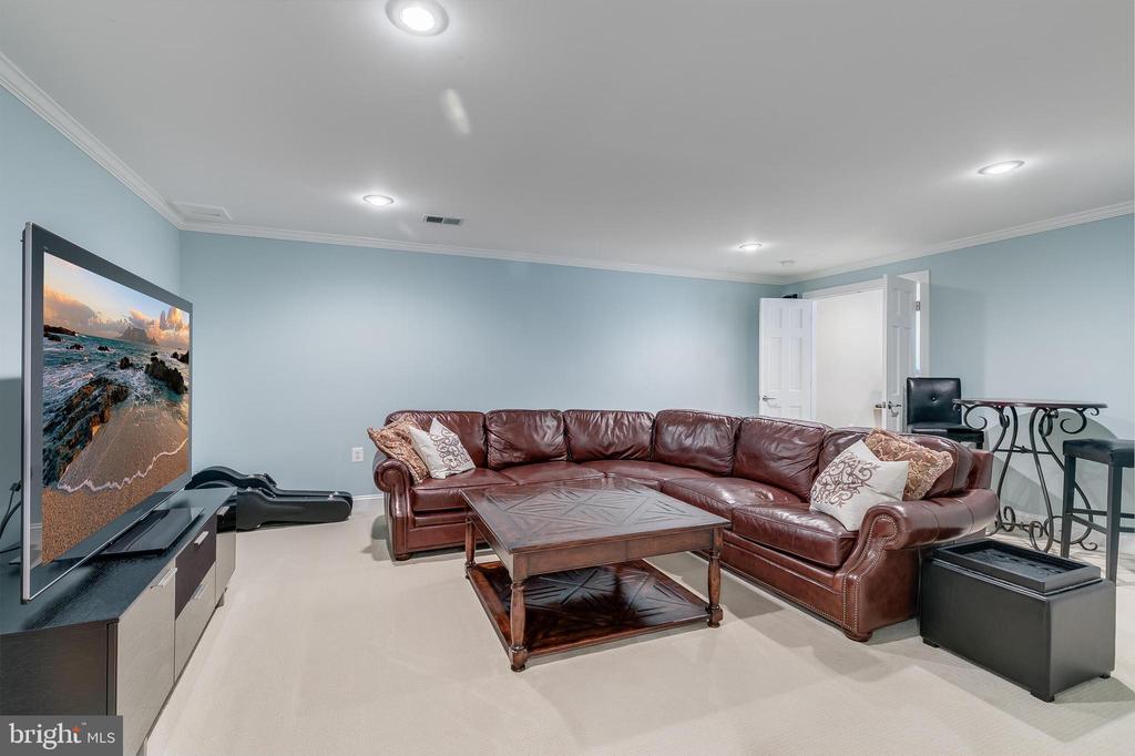 Living room with a brown leather sectional, wooden coffee table, and television.