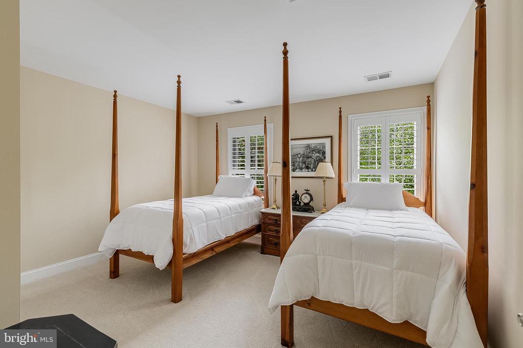 Bedroom with two wooden four-poster twin beds, white bedding, and shuttered windows.