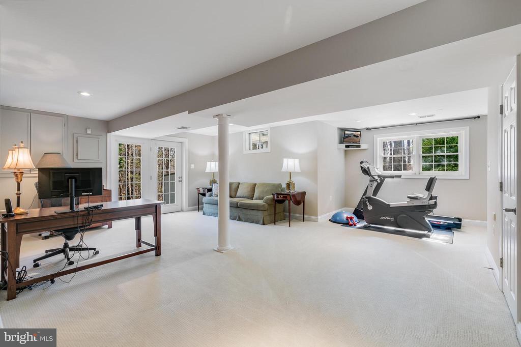 Furnished lower-level room with a home office, sofa, treadmill, and exercise equipment.