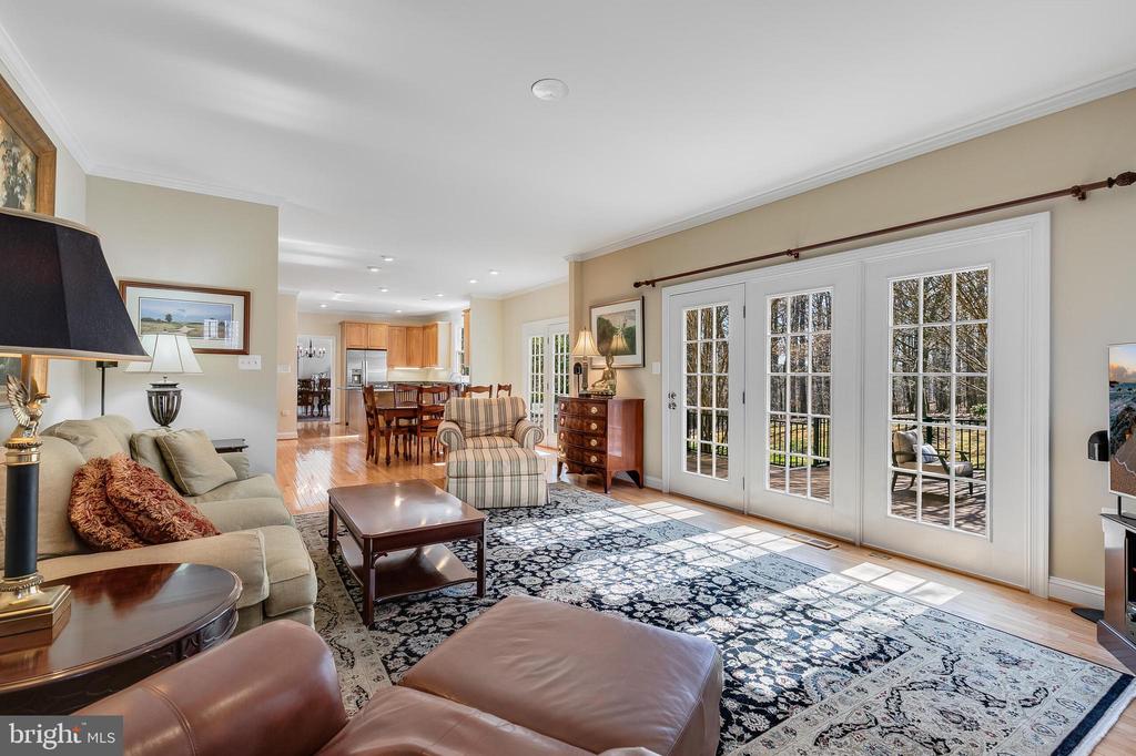 Furnished living room with French doors opening to a deck and wooded views.
