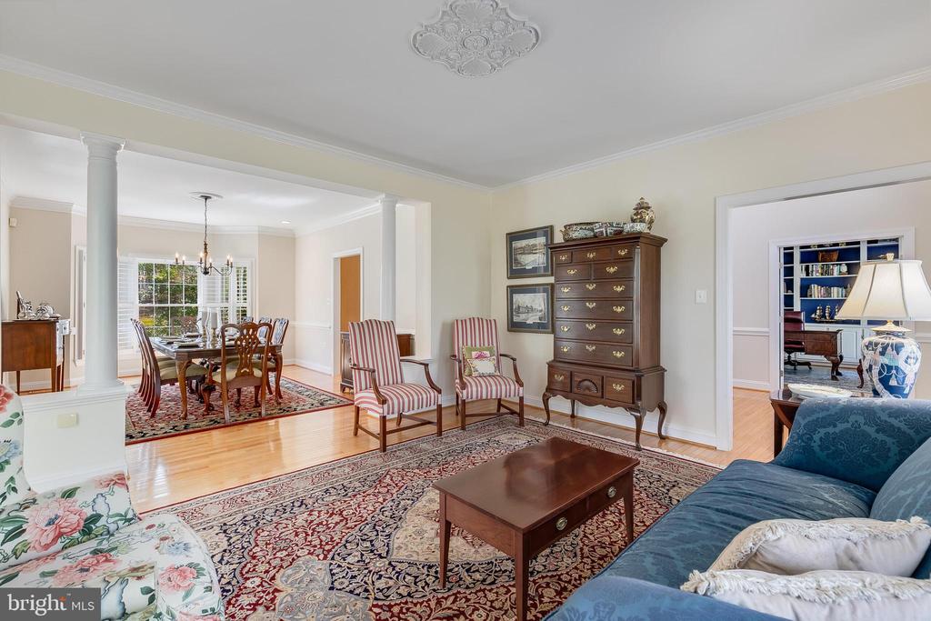 Living room with blue sofa and patterned rugs, opening to a dining room and study.