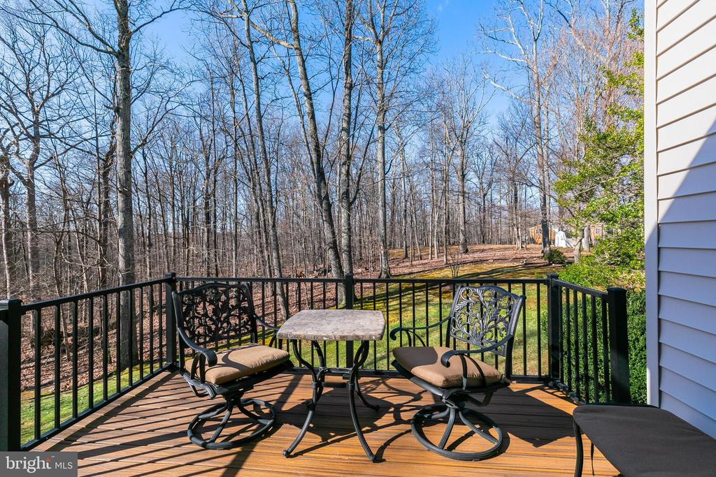Wooden deck with patio seating overlooking a leafless wooded backyard.