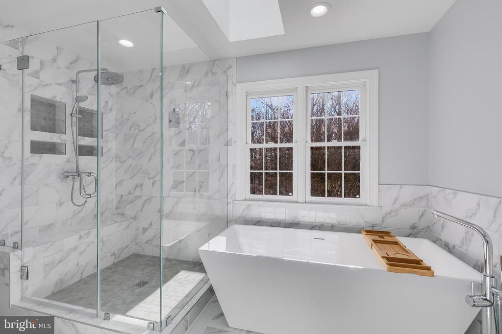 Marble-tiled bathroom with a freestanding tub and glass-enclosed shower.