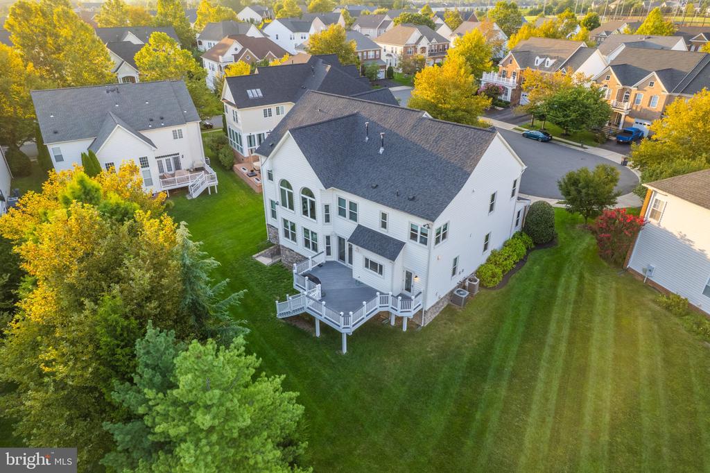 Aerial view of a white two-story house with a raised deck and broad lawn.