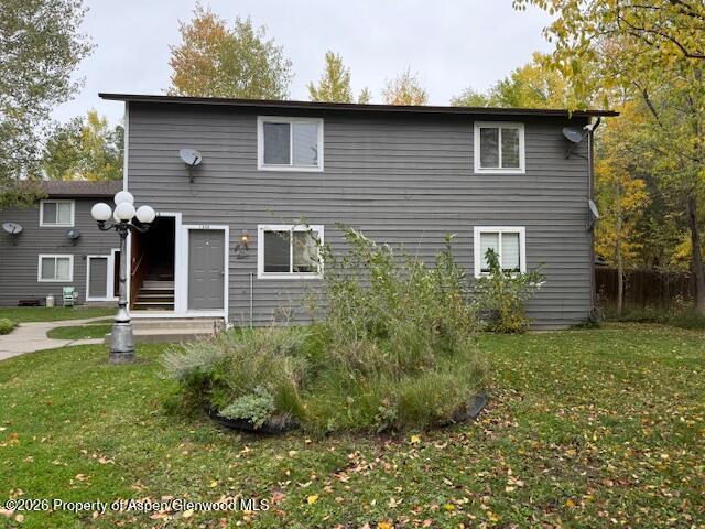 Two-story gray rental building with white-trimmed windows, an entry stairway, and autumn trees.