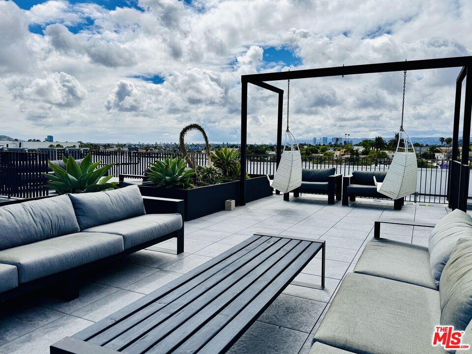 Rooftop terrace with hanging chairs, succulent planters, and a distant city skyline.