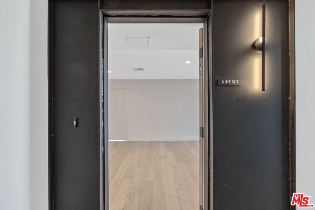 Unit 301 entryway opening onto a vacant room with light wood flooring and recessed lights.