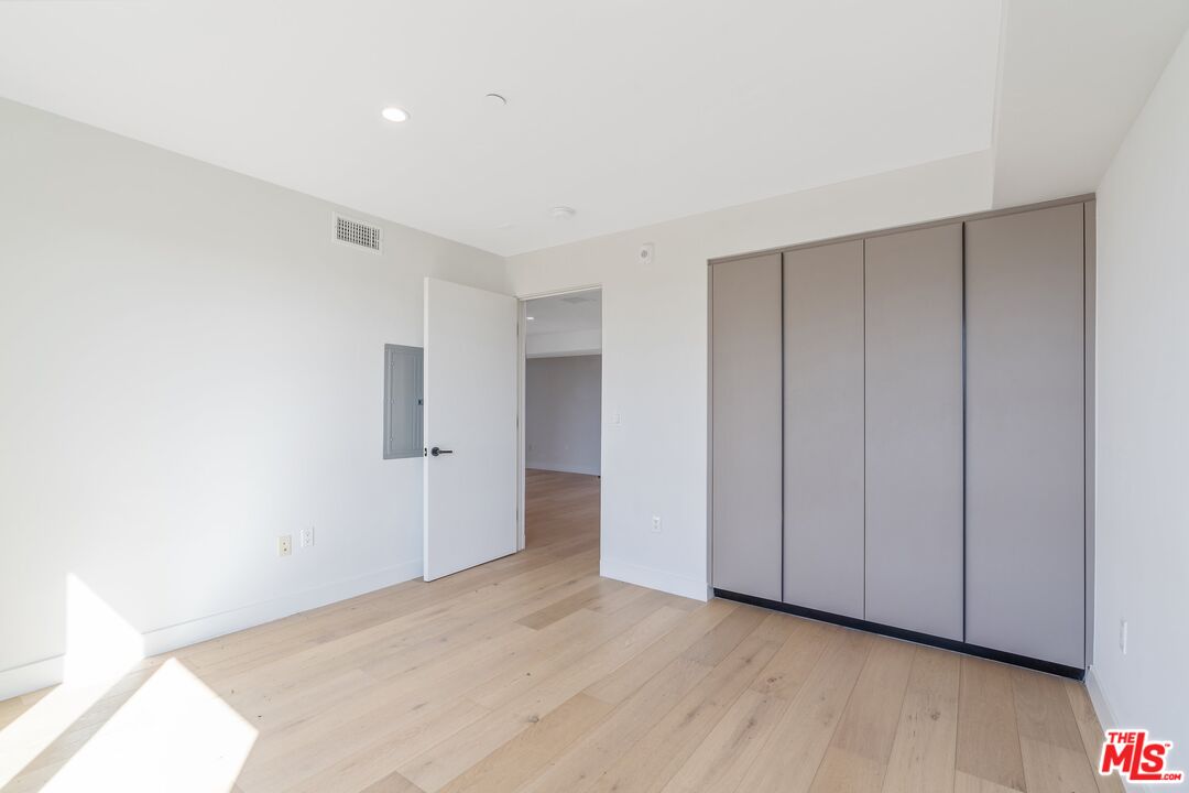 Vacant bedroom with pale wood floors and a large built-in closet with gray doors.