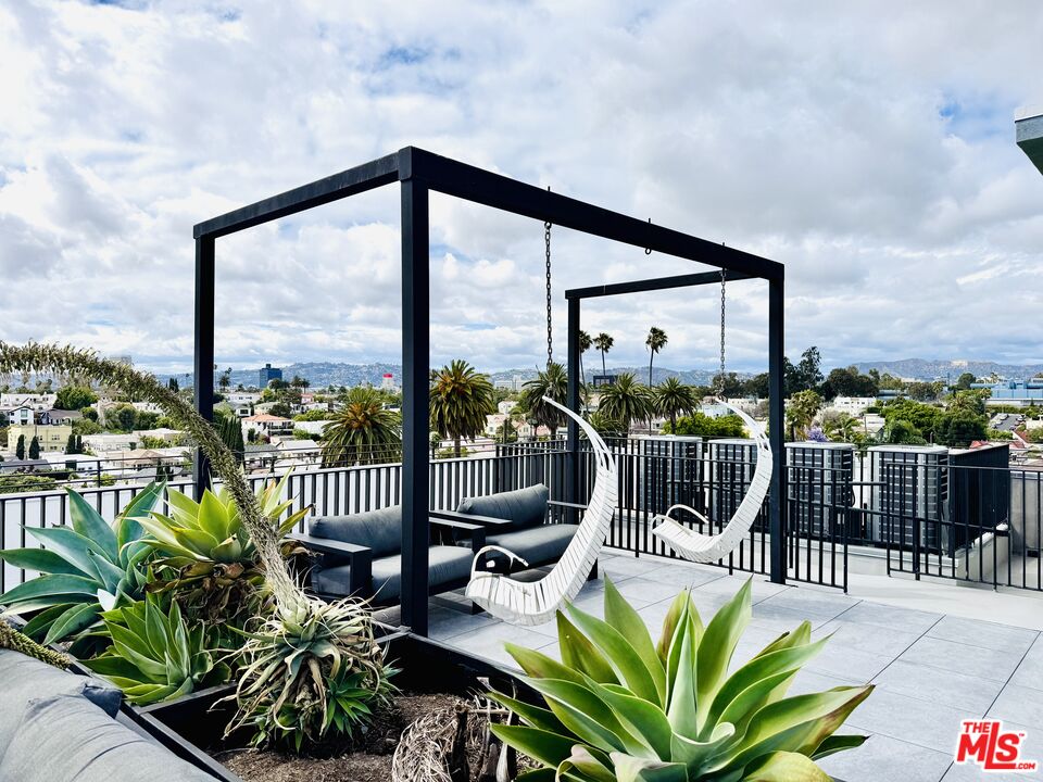 Rooftop terrace with hanging swing chairs, succulent planters, and views over Los Angeles.