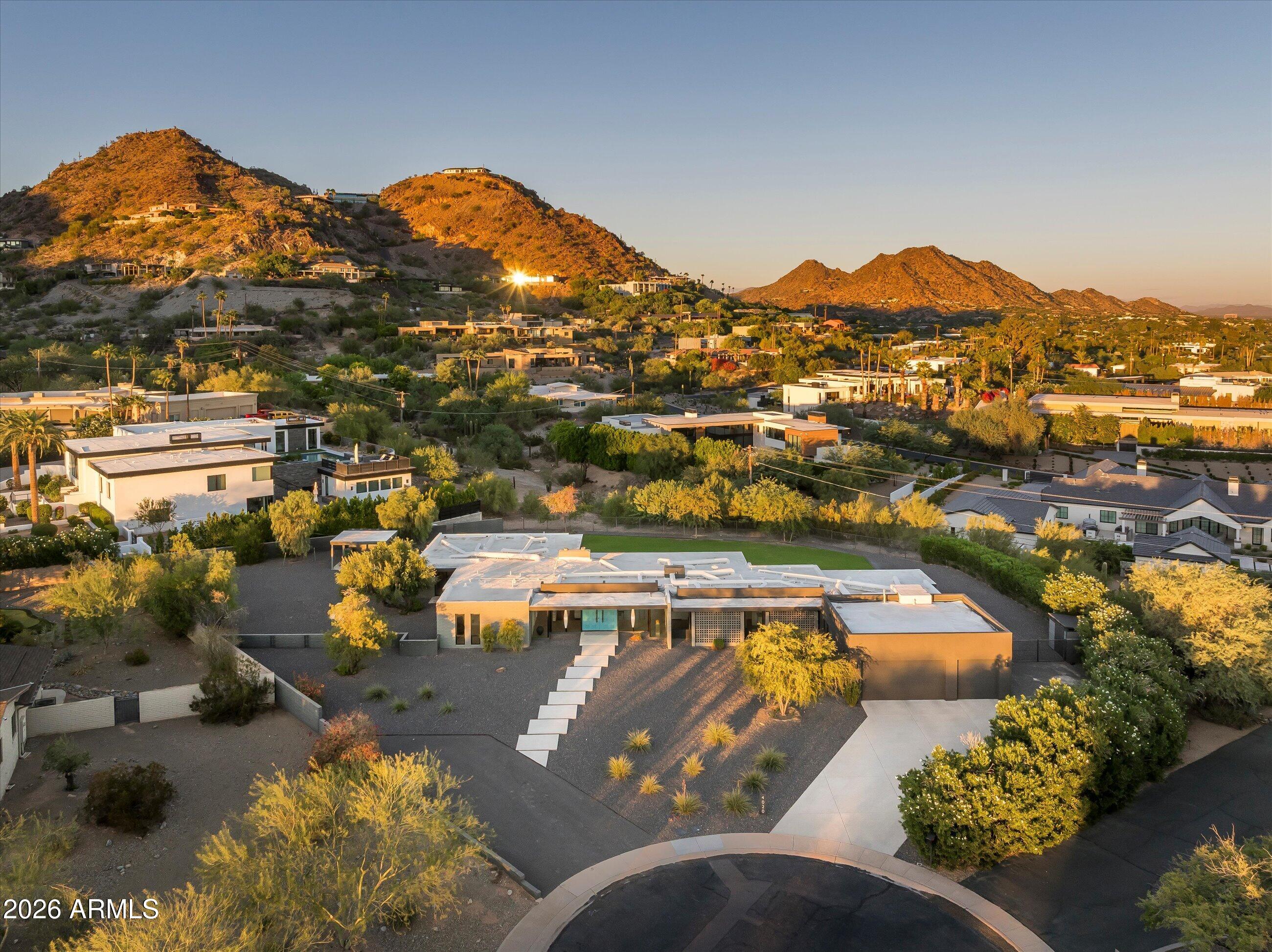 Aerial view of a modern desert home with a long stepping-stone path and mountains beyond.