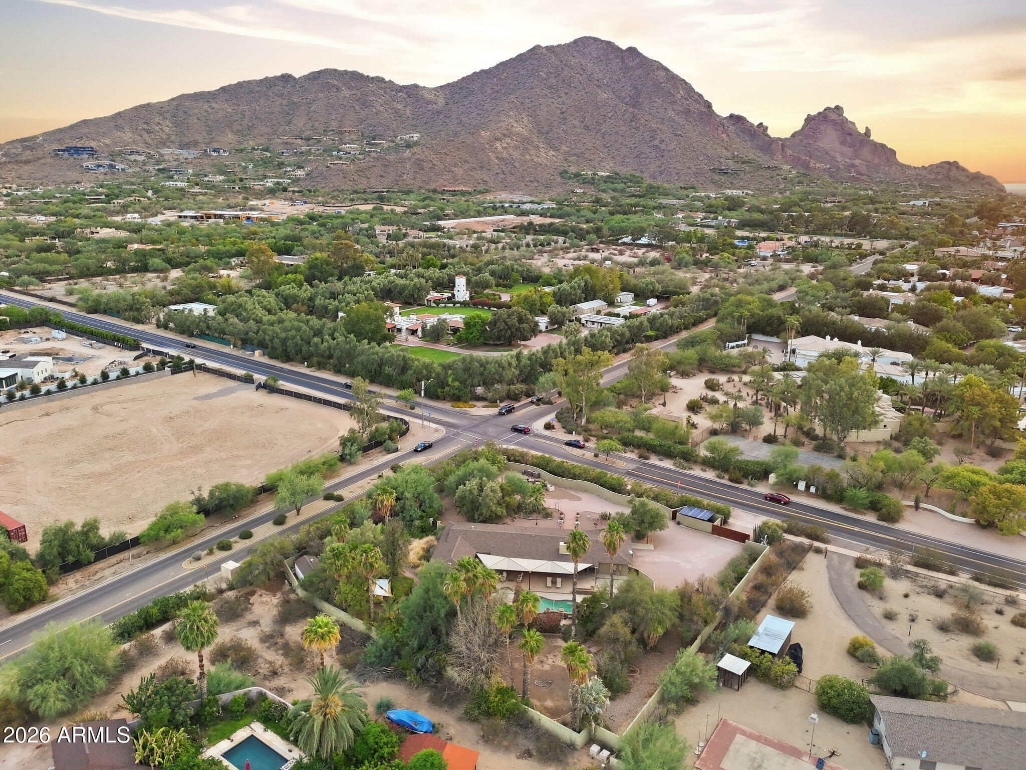 Aerial view of Paradise Valley homes and streets beneath Camelback Mountain at sunset.