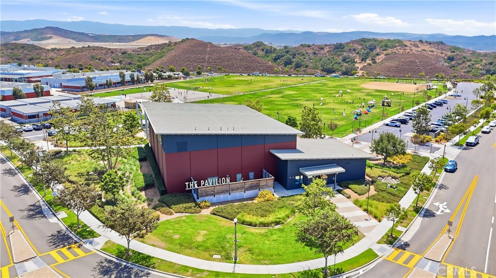 Community pavilion beside green sports fields, with hills and mountains in the distance.