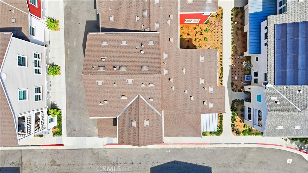 Aerial view of closely spaced homes with tiled rooftops beside a residential street.