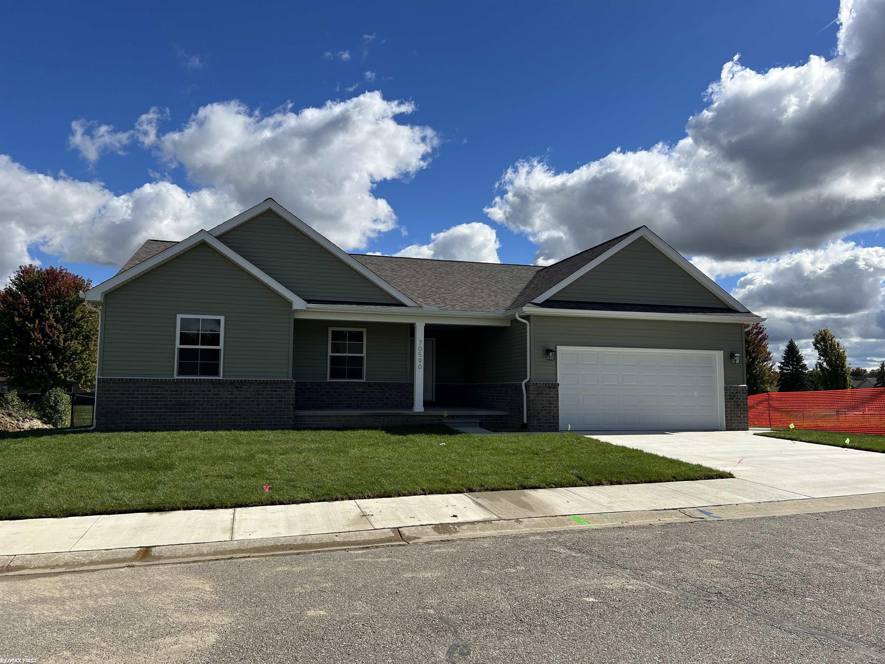 Single-story home with dark green siding, brick lower facade, and attached two-car garage.