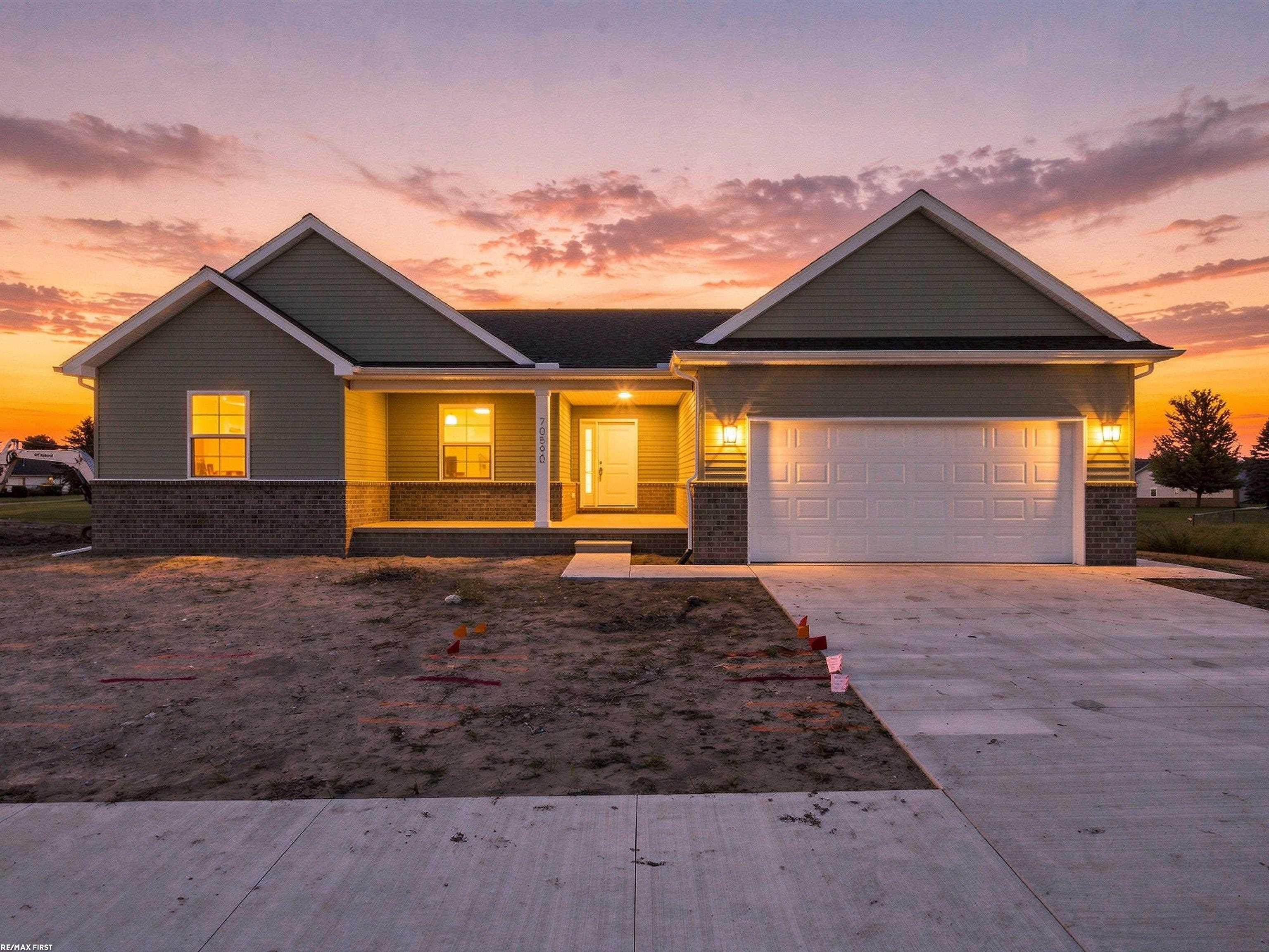 Gray single-story home with a covered porch and two-car garage at sunset.