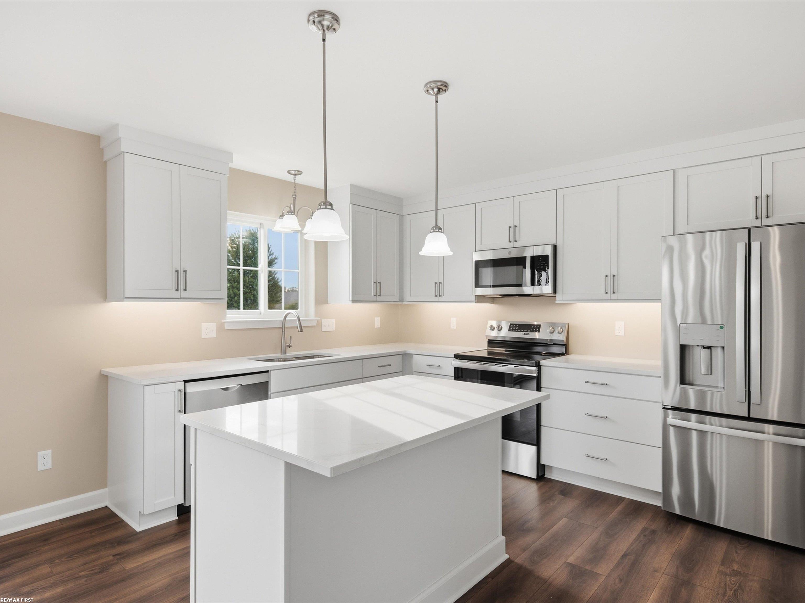 Bright kitchen with white cabinets, a large island, and stainless steel appliances.