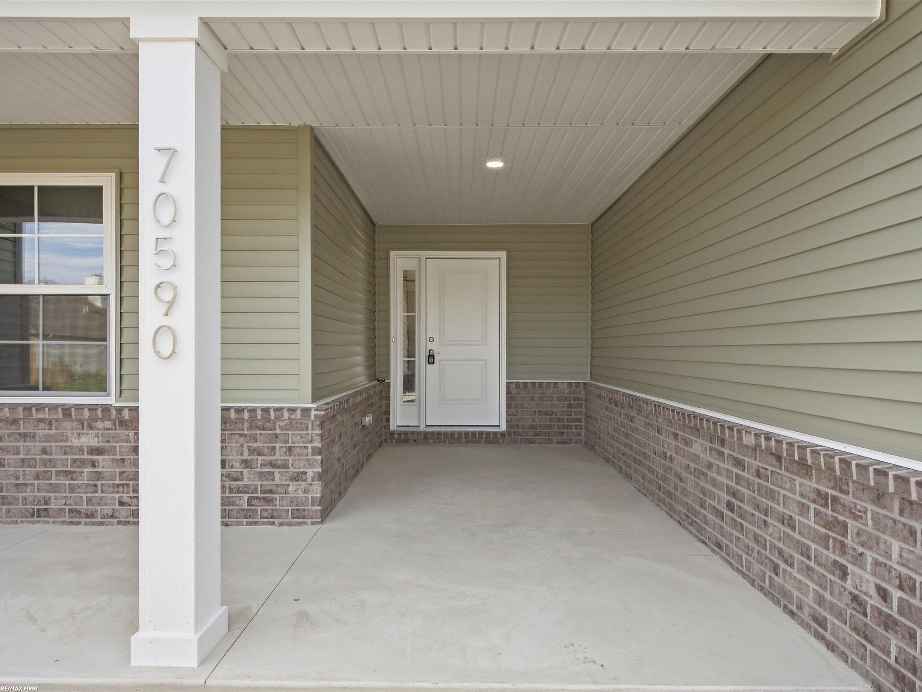 Covered home entry with address 70590 on a white column and brick half-walls.
