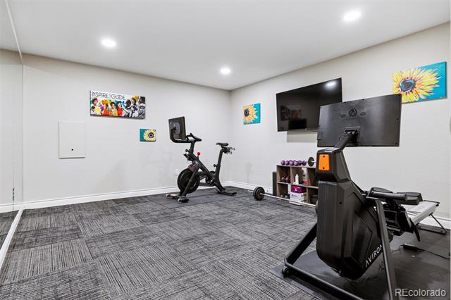 Home gym with a stationary bike, treadmill, free weights, and a wall-mounted television.