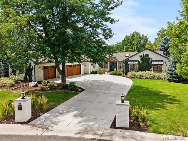 Single-story home with multiple garage doors and a curved driveway framed by mature trees.
