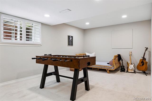 Game room with a wooden foosball table, chaise lounge, and guitars.