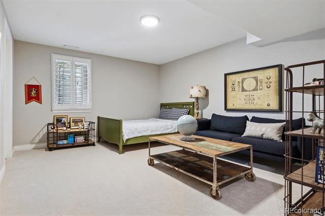 Bedroom with a green bed, dark sofa, and rolling coffee table.