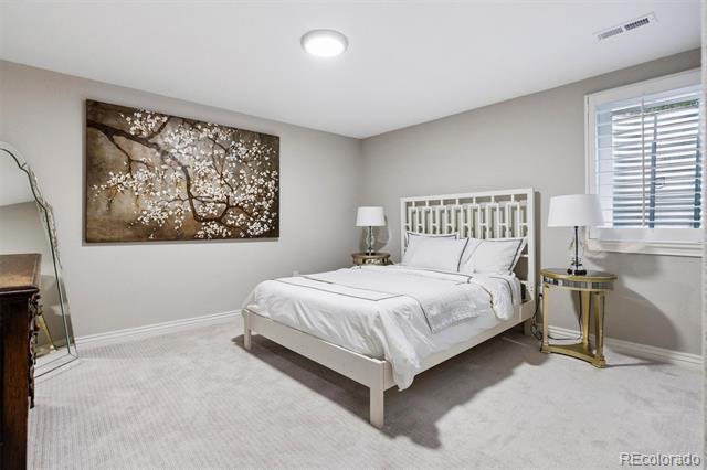Staged bedroom with a white bed, blossom-tree wall art, and a window with blinds.