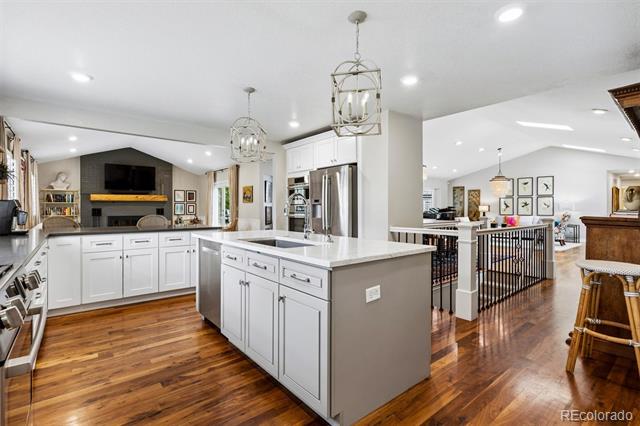 Open-plan kitchen with a large island, white cabinetry, stainless steel appliances, and hardwood floors.