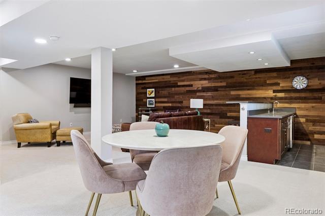 Finished basement dining and lounge area with a round table, wood-paneled wall, bar counter, and dartboard.