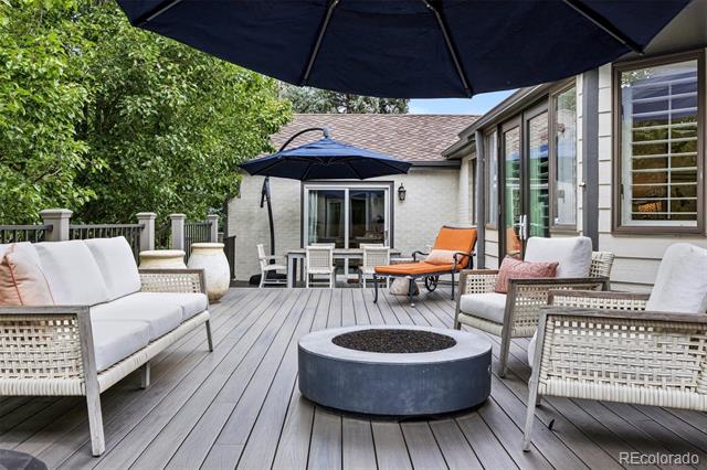 Outdoor deck with woven seating, a round fire pit, and navy umbrellas.