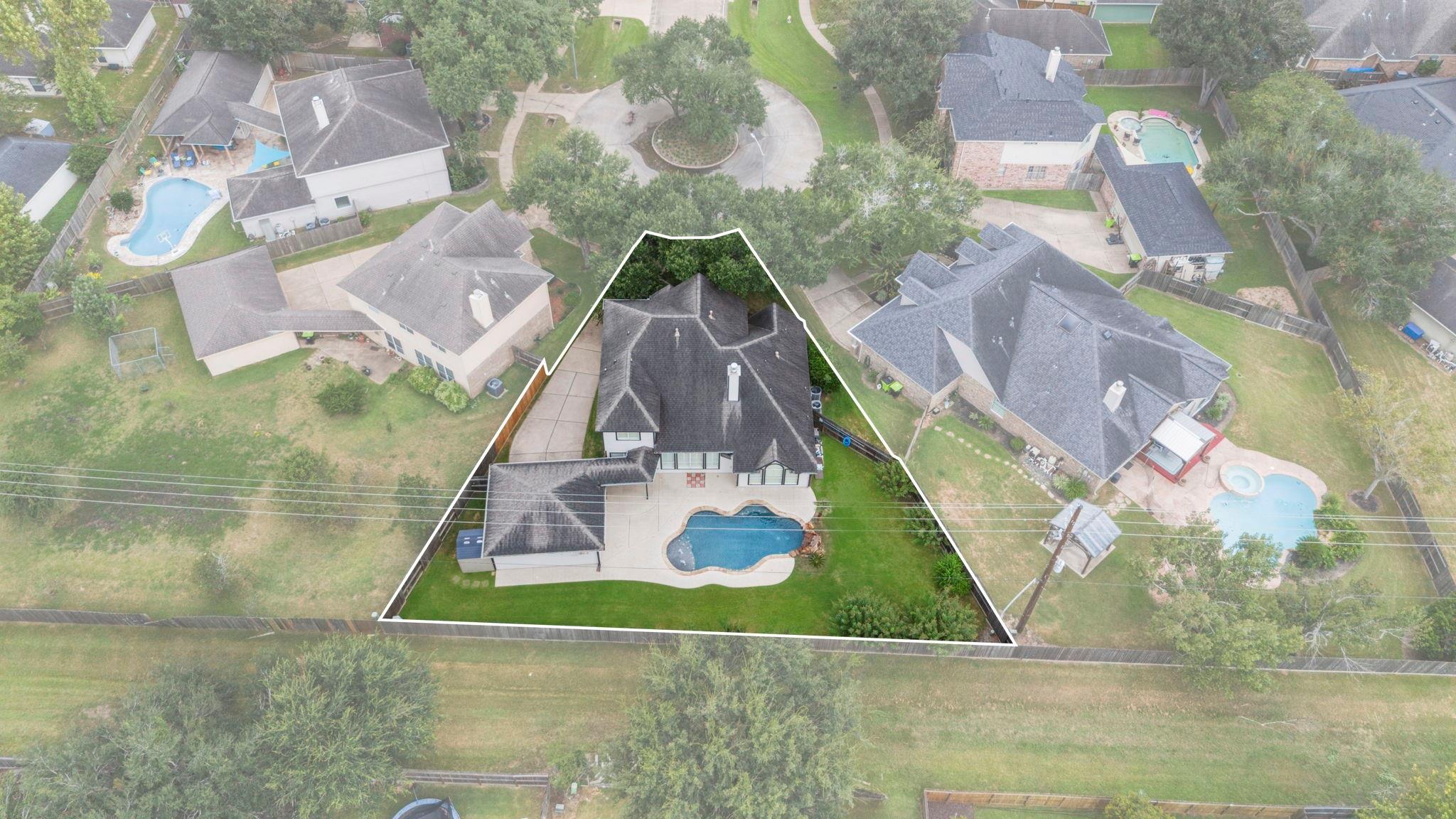 Aerial view of a house with a backyard pool, its lot outlined in white.