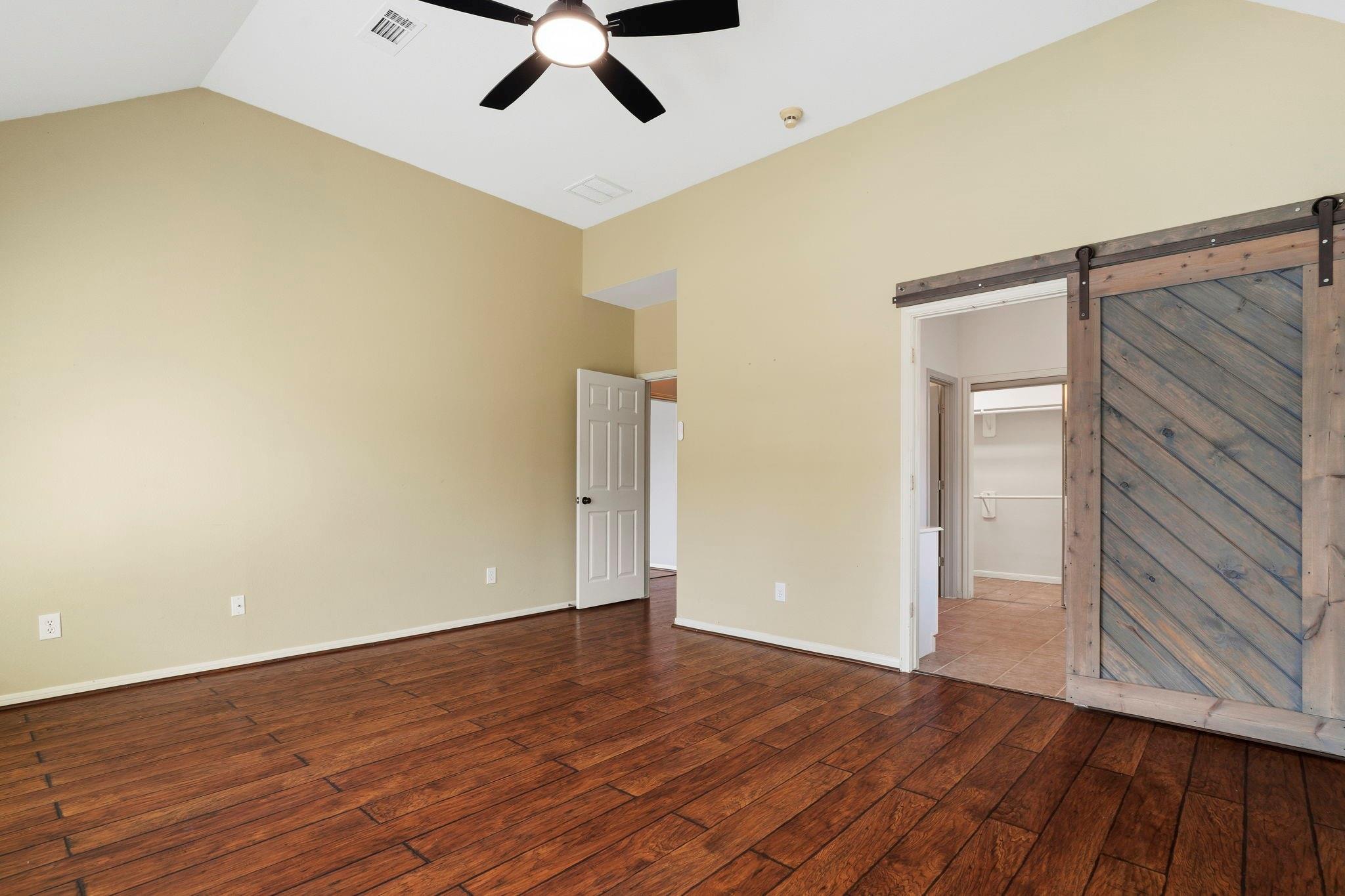 Empty bedroom with dark wood flooring and a rustic sliding barn door