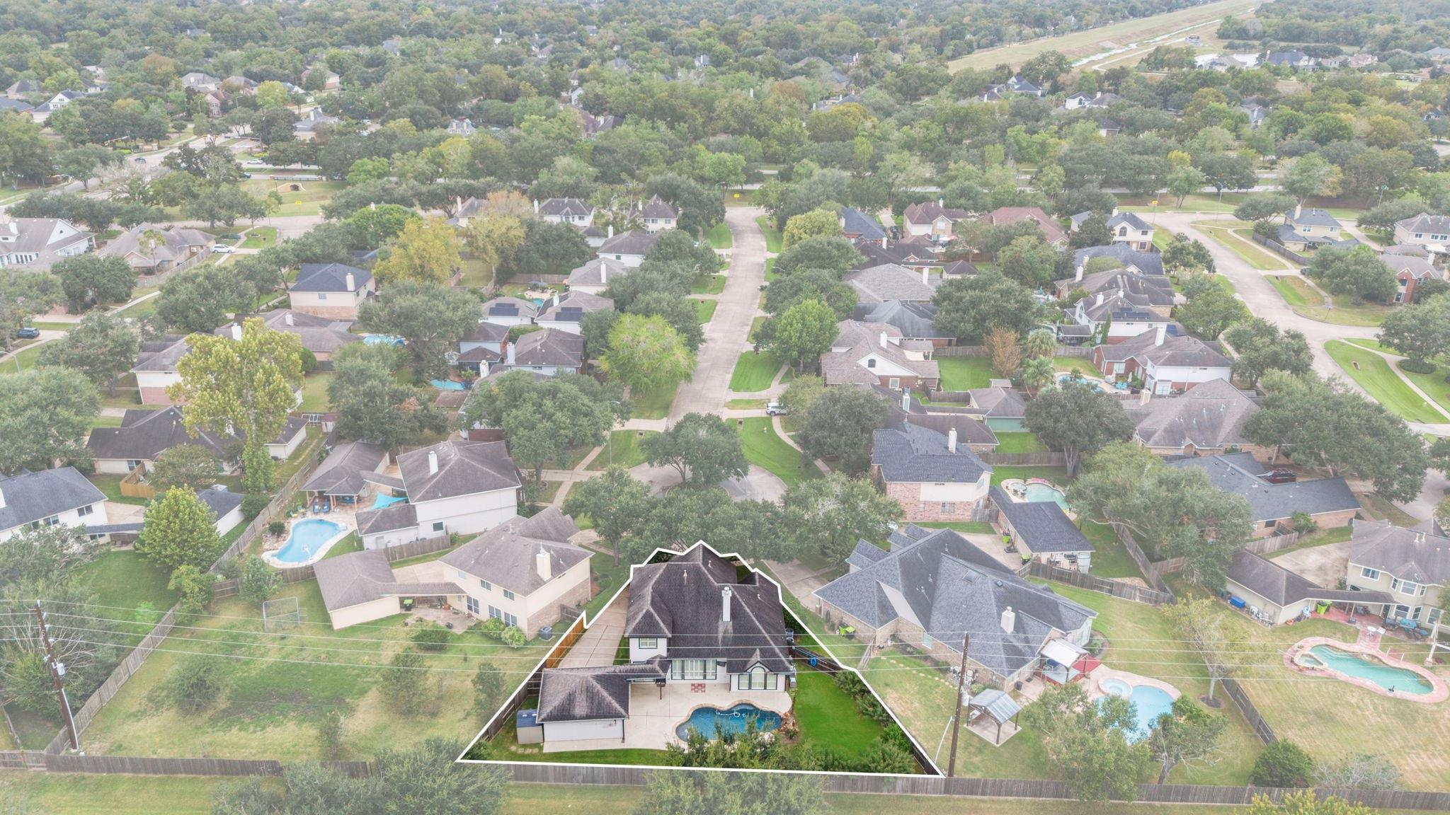 Aerial view of the outlined home, with a fenced backyard and swimming pool.