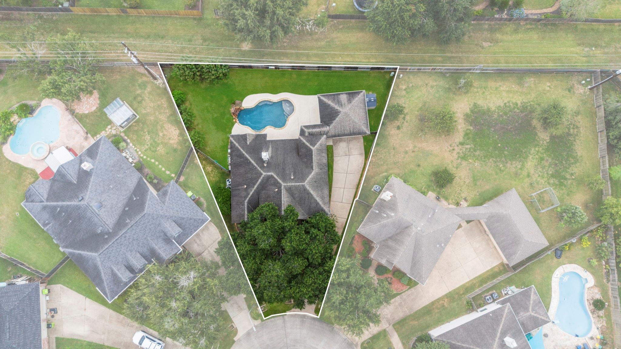 Aerial view of the outlined property, with a backyard pool, lawn, and driveway.