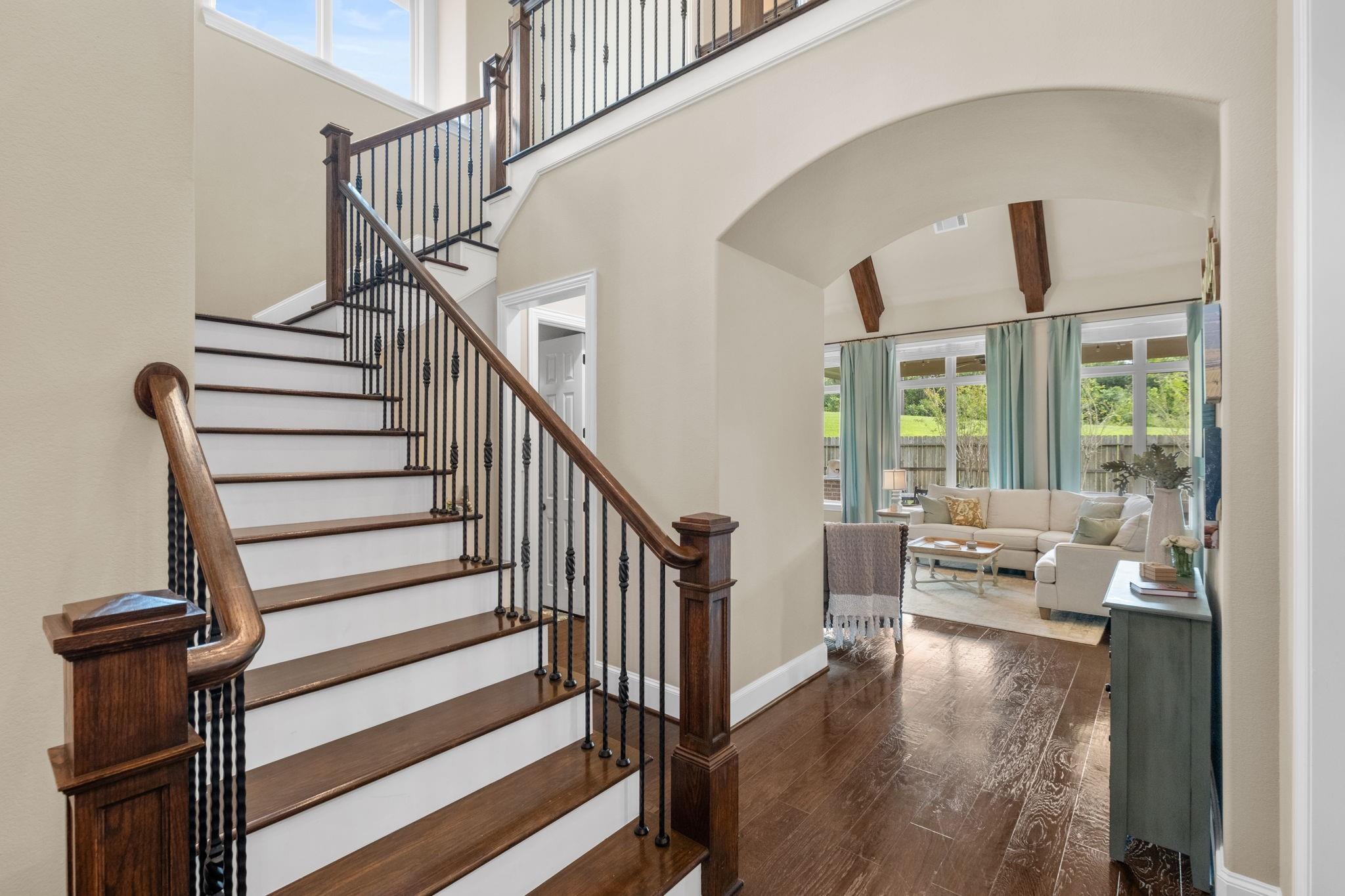 Foyer with a sweeping dark wood and iron staircase opening onto a bright living room.