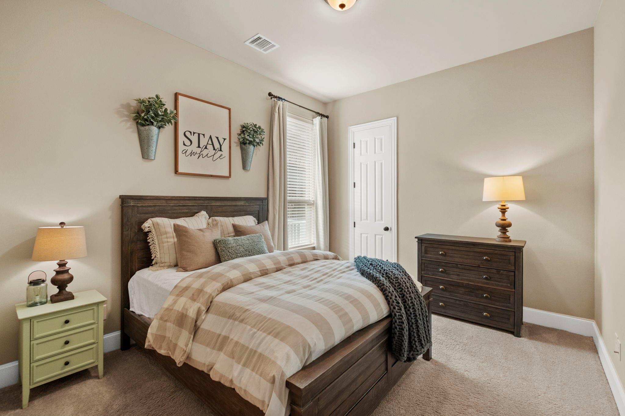 Bedroom with a dark wood bed, neutral plaid bedding, and matching dresser.
