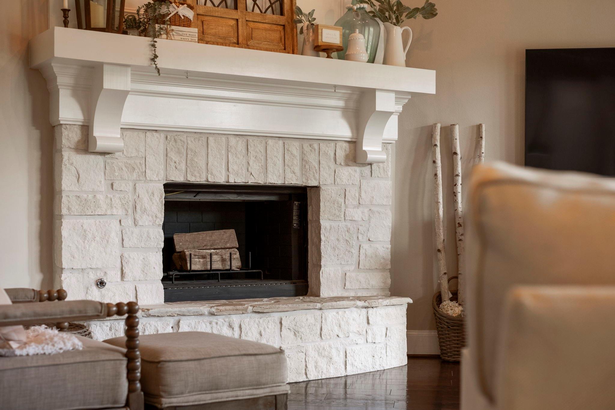 Living room fireplace with a white stone surround, ornate mantel, and dark firebox.