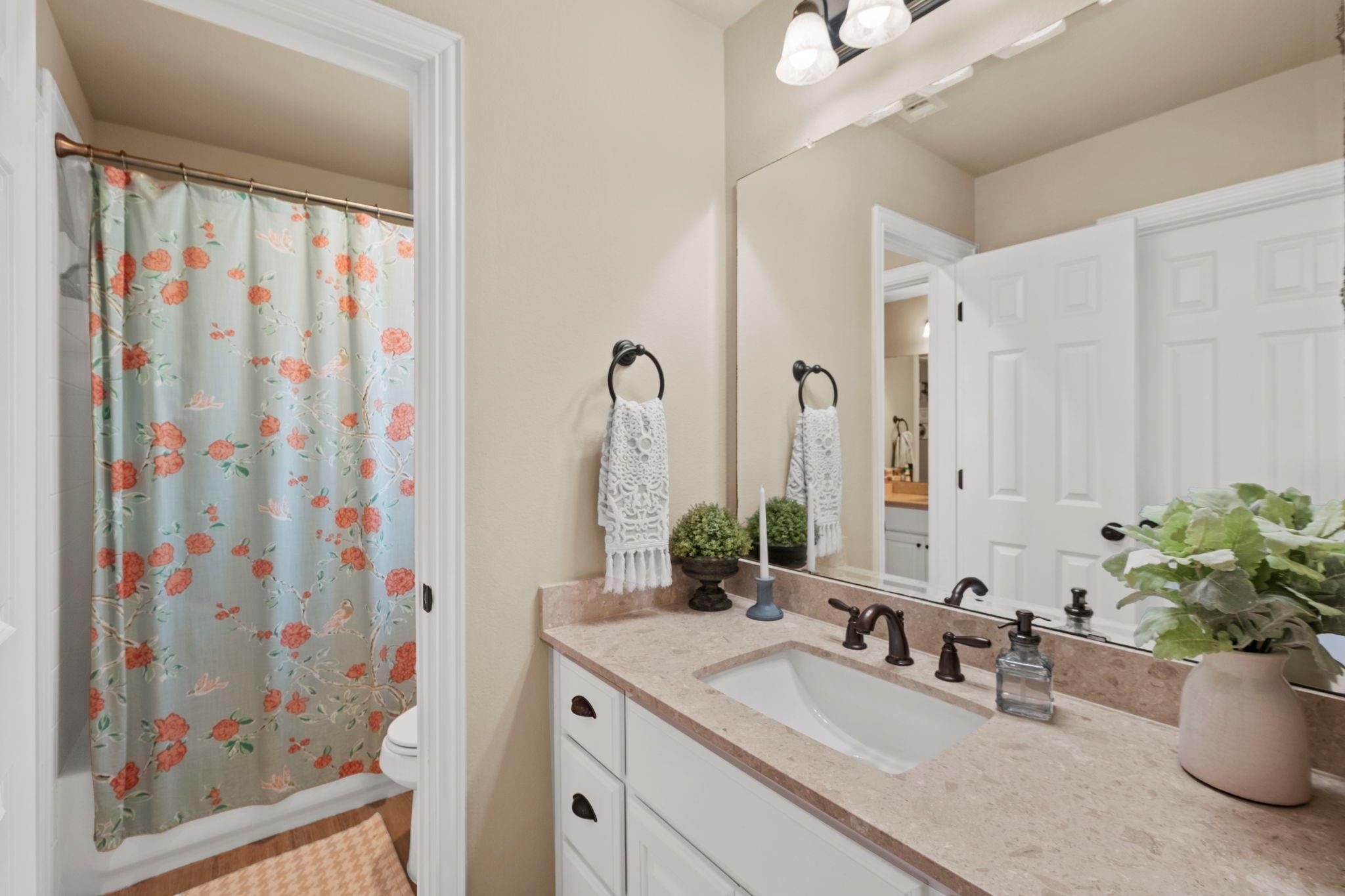 Bathroom with a white vanity, large mirror, and blue floral shower curtain.