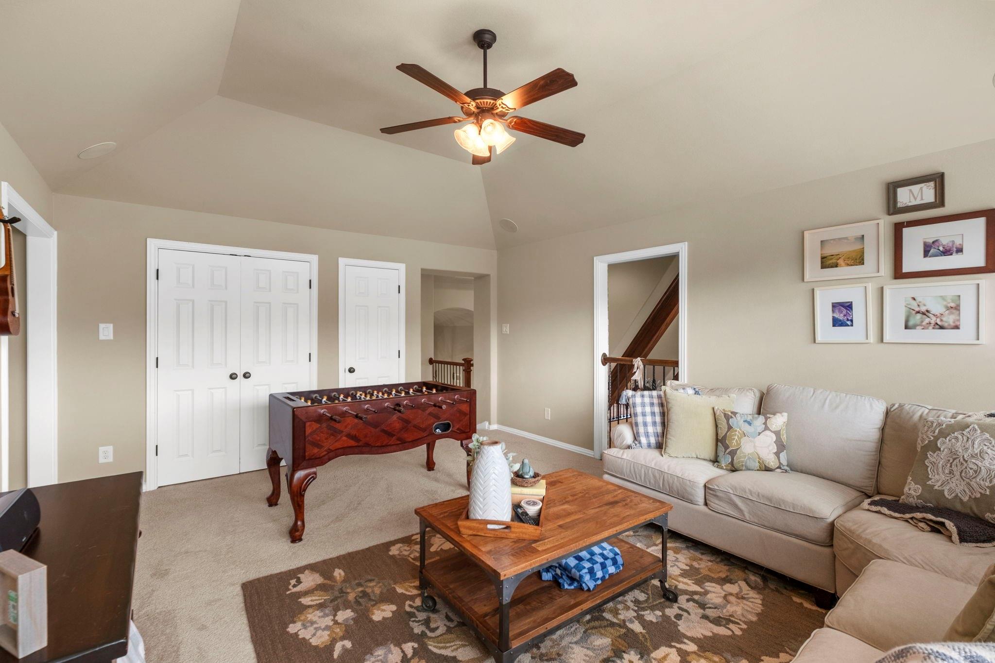 Furnished living room with a foosball table, large sectional sofa, and vaulted ceiling.